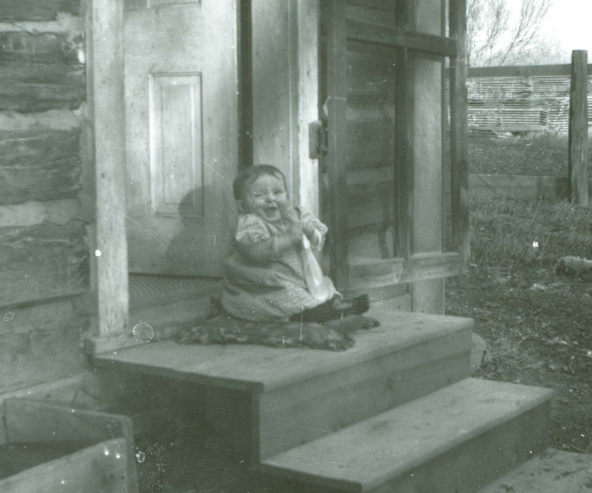 Baby Ruth Asbridge sitting on steps at Lazy X Ranch near Roundup, MT