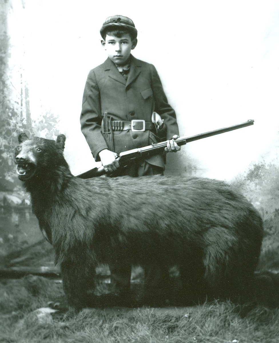 84-274,boy with rifle posed with stuffed bear.jpg