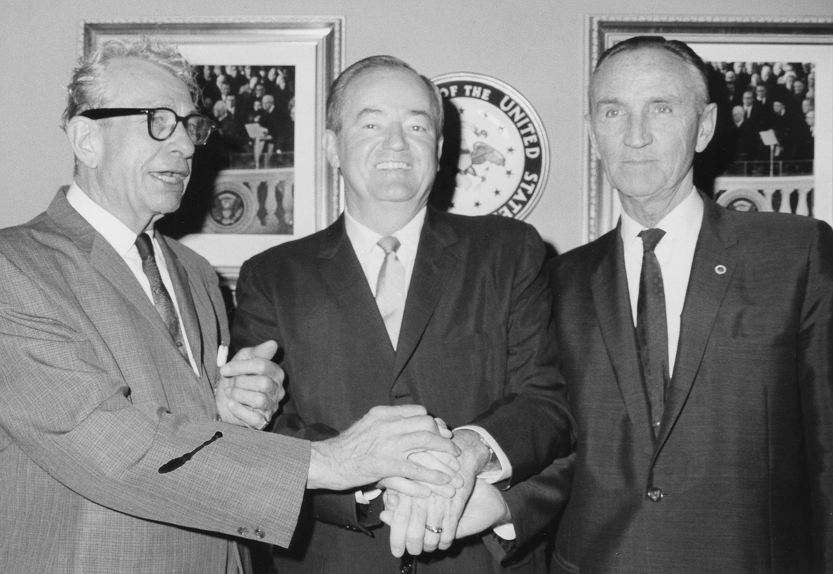 Senators Mike Mansfield and Everett Dirksen standing in a three-way handshake with Vice President Hubert H. Humphrey.