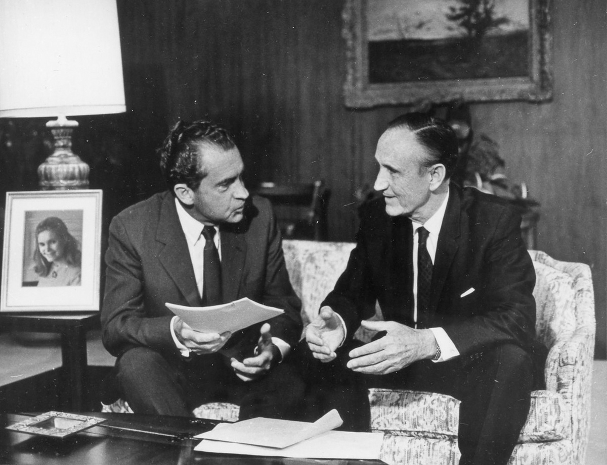 President Richard Nixon and Senator Mike Mansfield seated on a couch and looking at each other.