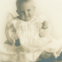 Seated baby in ruffled christening gown
